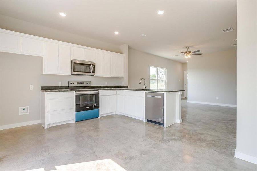 Kitchen featuring stainless steel appliances, white cabinets, ceiling fan, sink, and kitchen peninsula