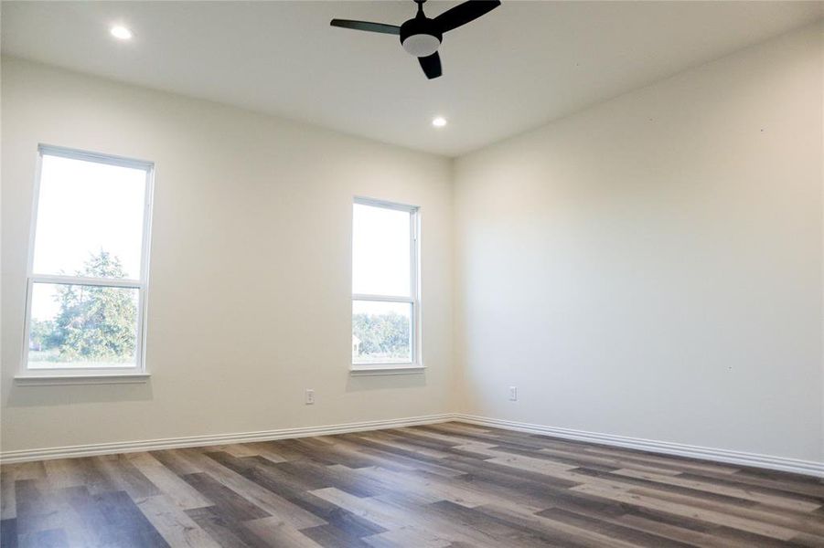 Spare room featuring ceiling fan, dark hardwood / wood-style floors, and plenty of natural light