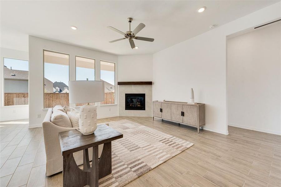 Living room featuring ceiling fan, light hardwood / wood-style flooring, and a tiled fireplace