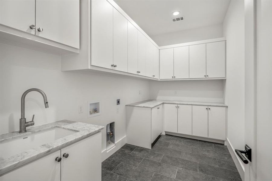 Second floor utility room with ample storage, sink, and space to accommodate a full sized washer and dryer.