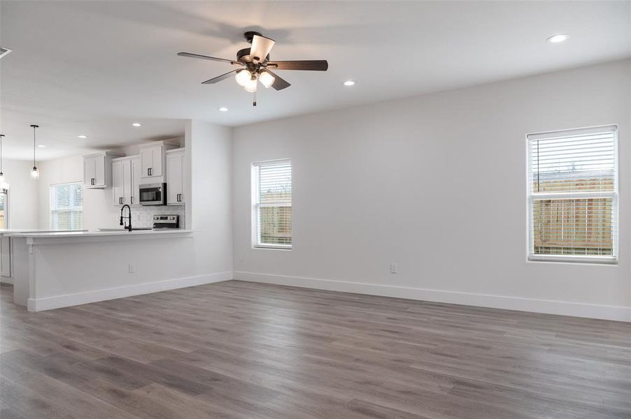 Unfurnished living room featuring sink, wood-type flooring, and ceiling fan