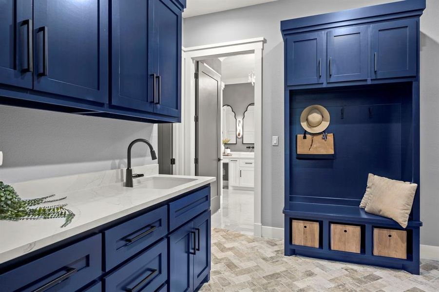 Laundry room conveniently located off primary suite includes handcrafted lockers, tile floor, and undermount sink in quartz countertops. Beautiful craftmanship throughout the home