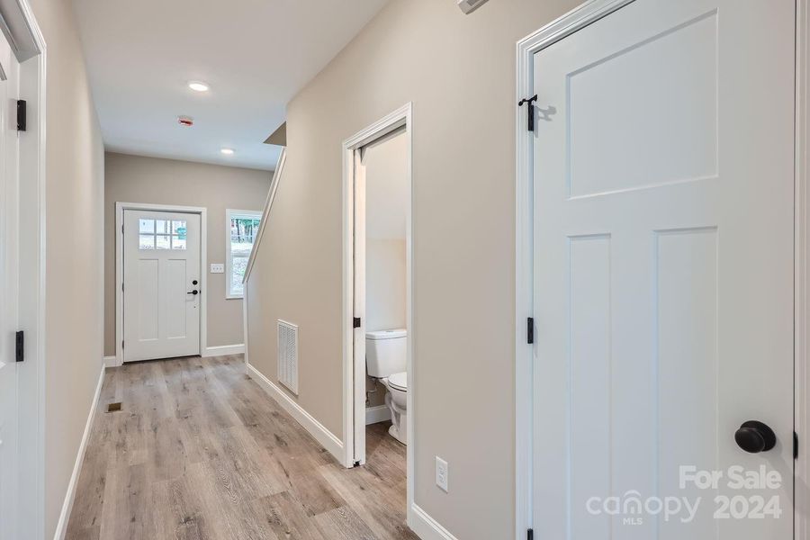 Welcoming entryway with handy half bath and jacket closet for guests.