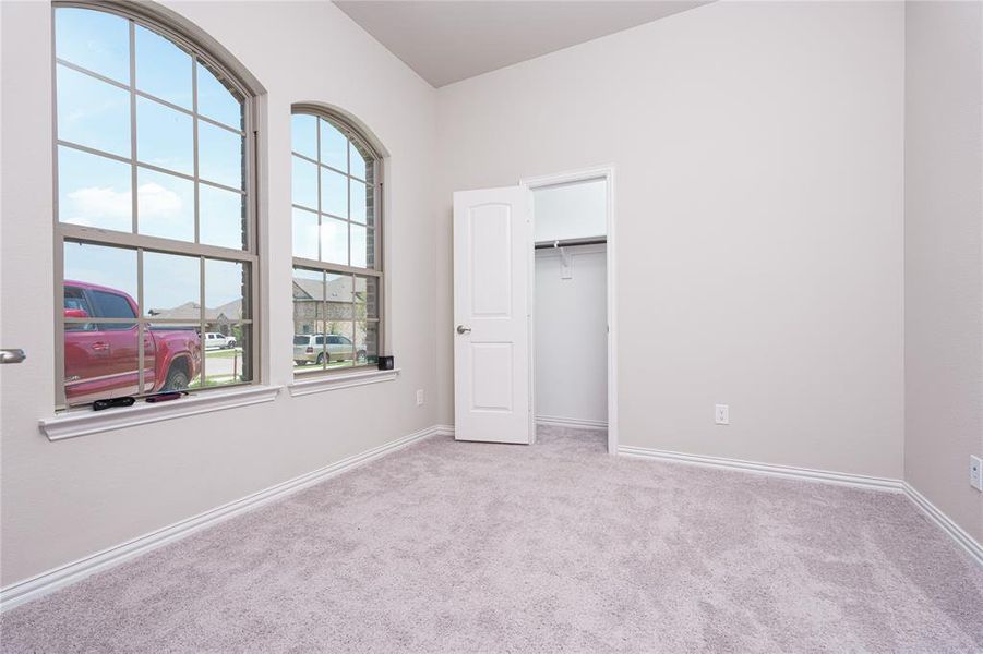 Unfurnished bedroom with light carpet, a closet, and a walk in closet