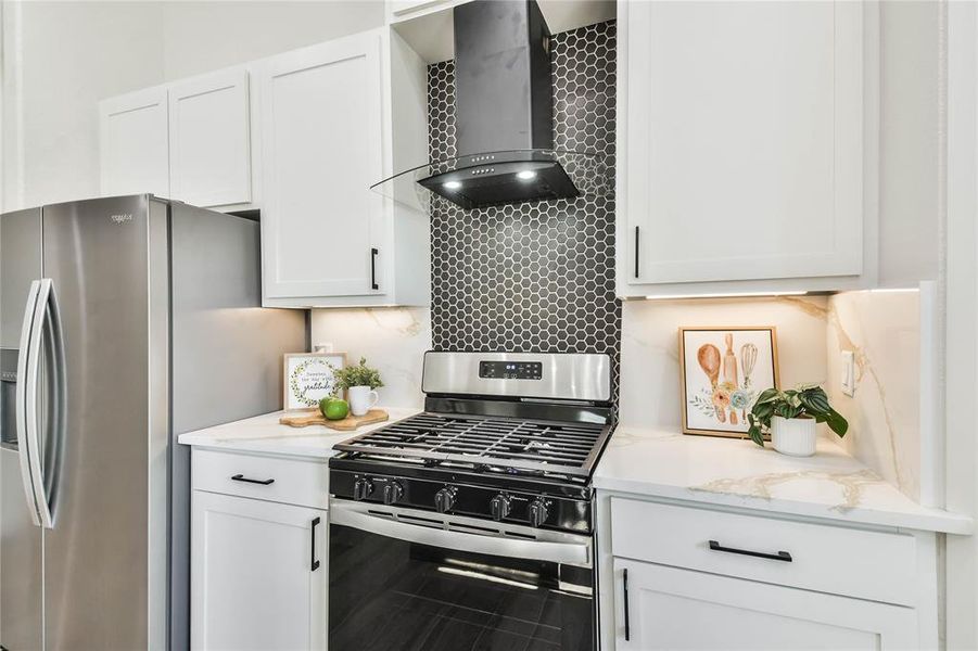 Gorgeous 5 burner gas stove and matte black vent hood with black decorative tile backsplash.