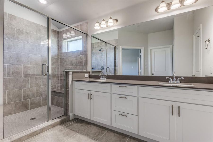 Bathroom featuring double vanity, an enclosed shower, and tile flooring