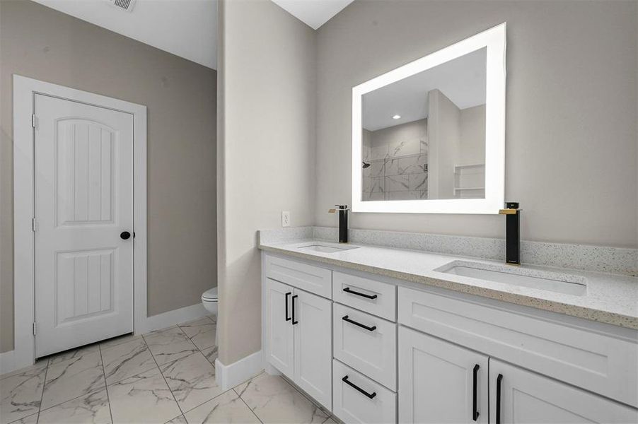 Bathroom featuring dual vanity, tile patterned flooring, and toilet