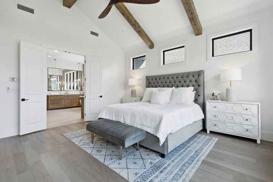 Bedroom with beam ceiling, ensuite bath, high vaulted ceiling, ceiling fan, and light wood-type flooring