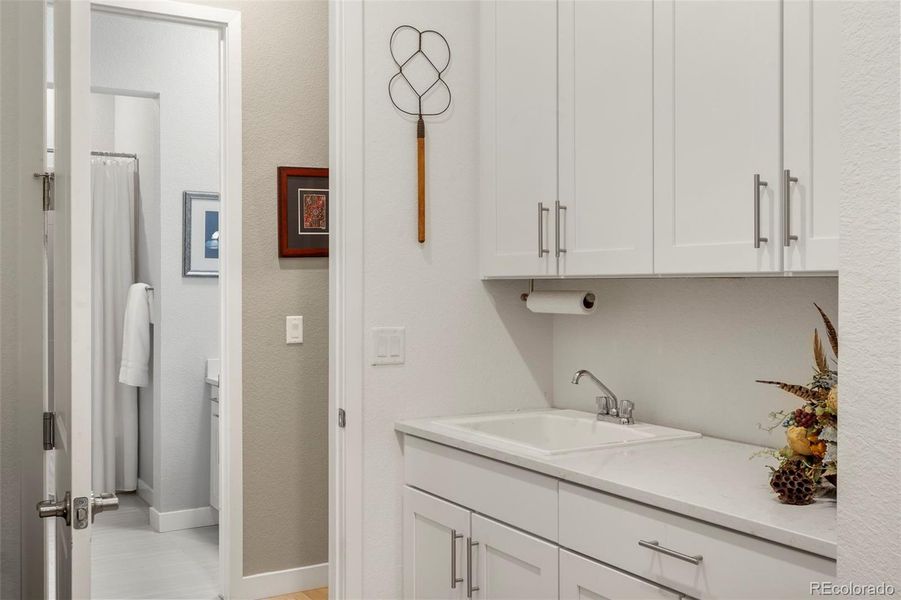 Laundry room with tons of cabinetry, utiity sink and convenient access to primary bedroom closet