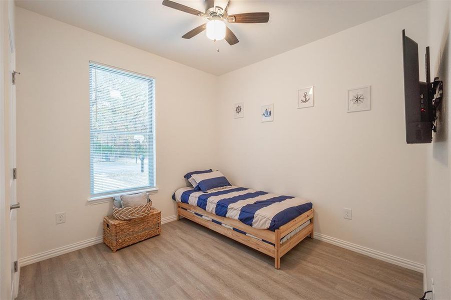 Bedroom with light wood-type flooring, multiple windows, and ceiling fan