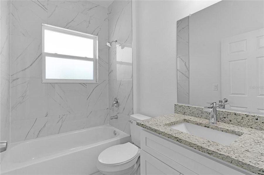 Guest bathroom with tiled tub surround and granit countertop