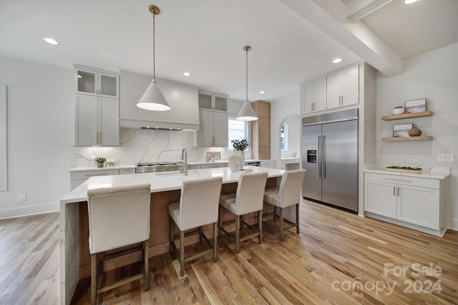 Kitchen includes built-in refrigerator, gas range, dishwasher, dual oven, and quartz backsplash.