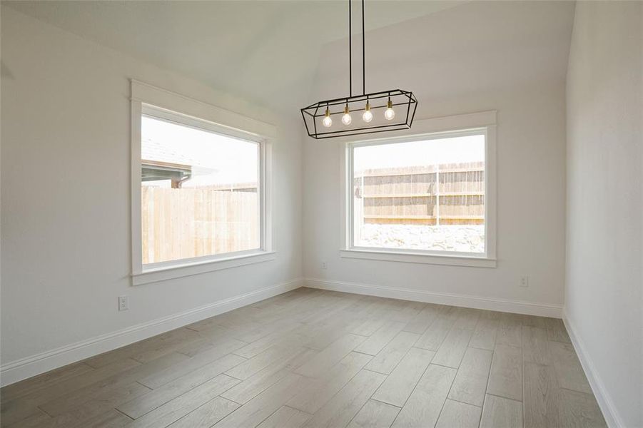 Spare room with light hardwood / wood-style floors and a chandelier