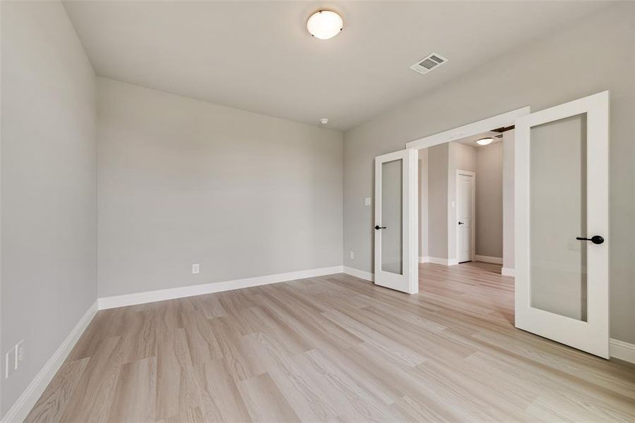 Unfurnished bedroom with light hardwood / wood-style flooring and french doors