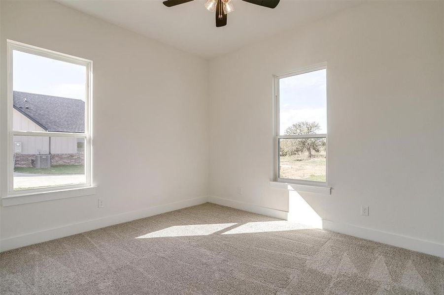 Carpeted spare room with a healthy amount of sunlight and ceiling fan