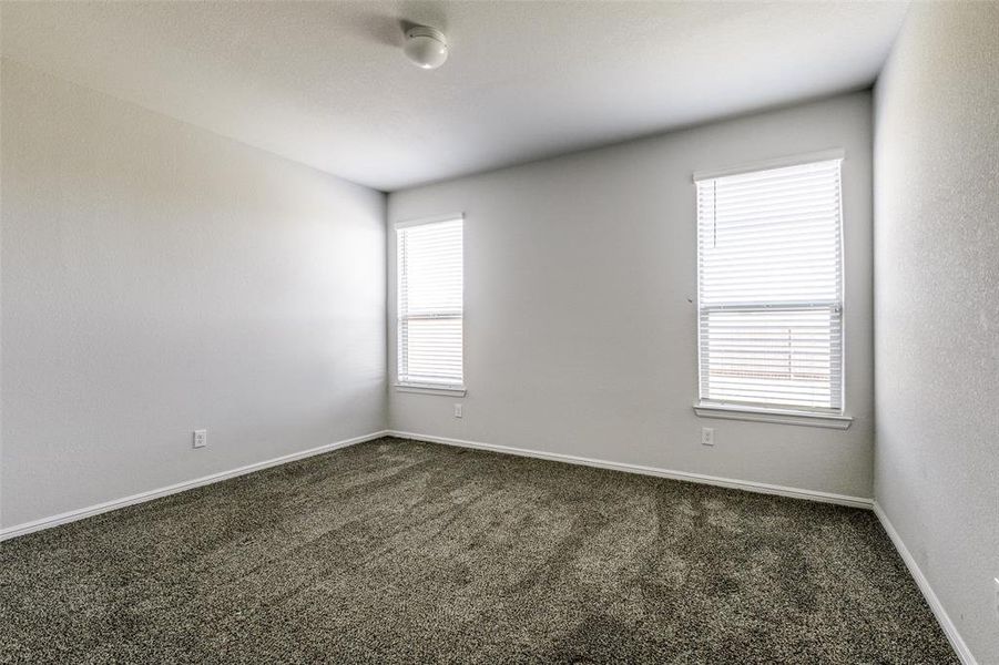 Spare room with dark colored carpet and a wealth of natural light