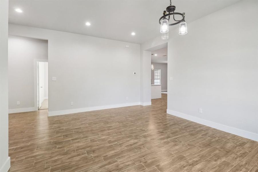 Unfurnished room featuring light wood-type flooring and a notable chandelier