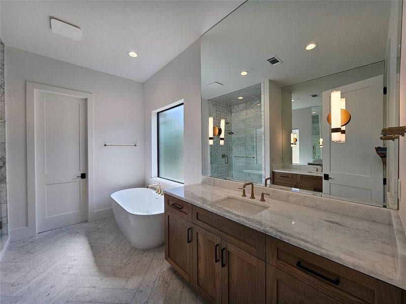 Primary Bathroom features a free standing tub as well as separate his & hers marble countertops
