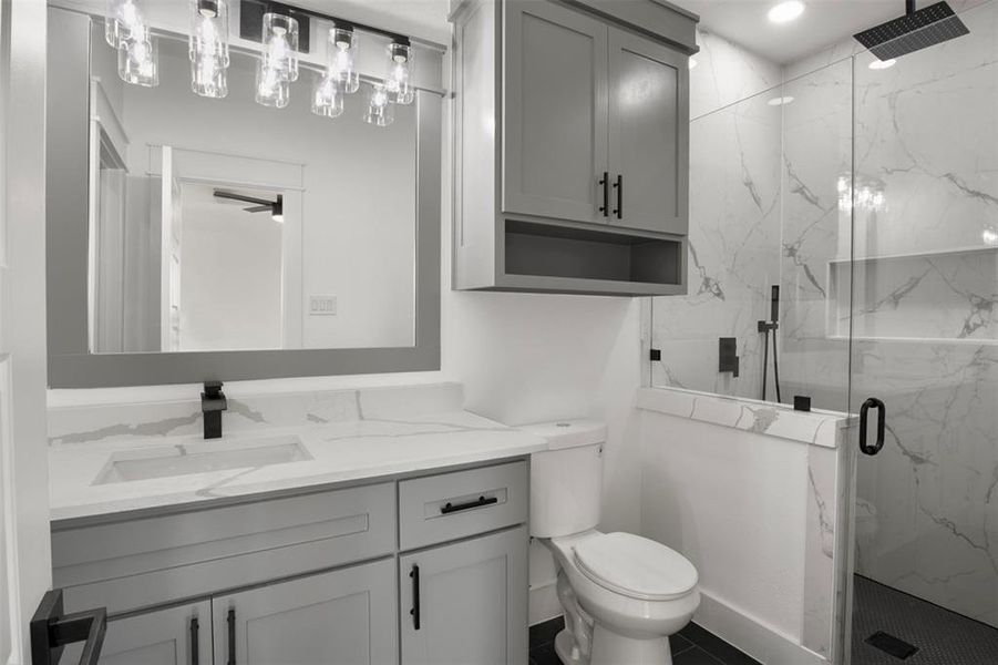 Bathroom with vanity, a shower with shower door, and toilet