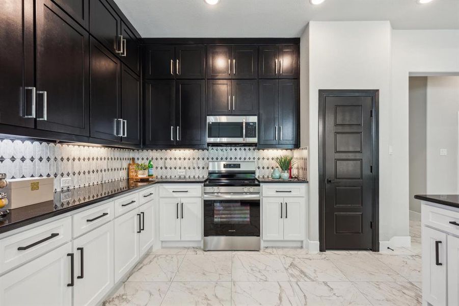 Kitchen with appliances with stainless steel finishes, white cabinetry, tasteful backsplash, and light tile floors