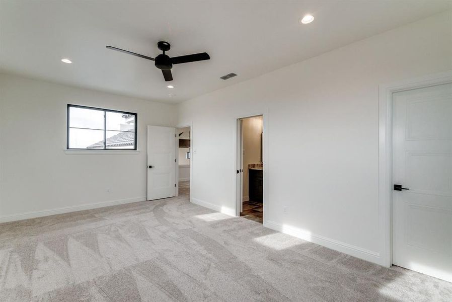 Unfurnished bedroom with ensuite bath, ceiling fan, and light colored carpet