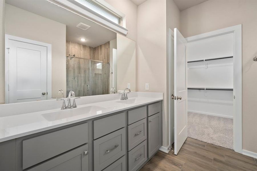 This primary bathroom is definitely move-in ready! Featuring a steel framed walk-in shower with tile surround, grey cabinets with light countertops, spacious walk-in closet with shelving, neutral paint and sleek modern finishes.