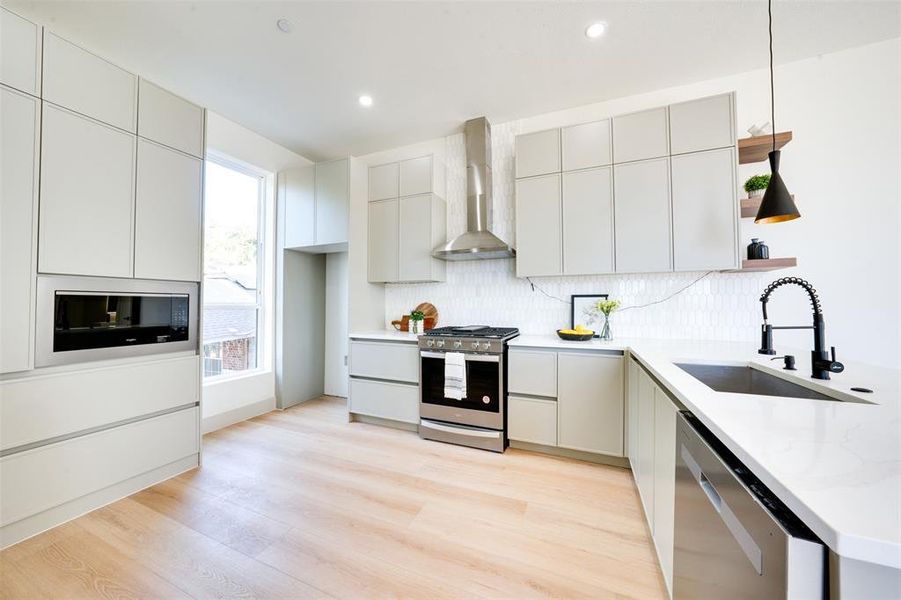 Kitchen featuring light hardwood / wood-style floors, stainless steel appliances, sink, and hanging light fixtures