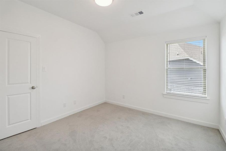 Carpeted empty room featuring vaulted ceiling