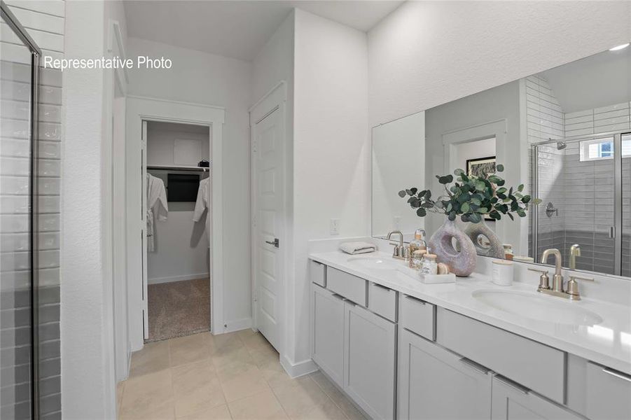 Bathroom with a shower with door, vanity, and tile patterned floors