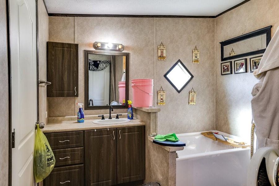 Bathroom with a textured ceiling, ornamental molding, and vanity