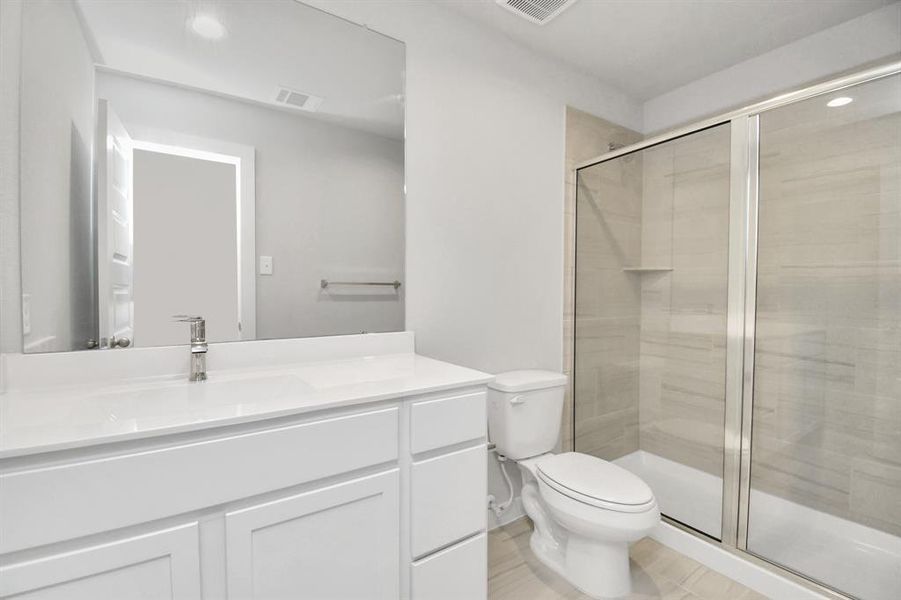 Secondary bath features tile flooring, walk-in shower with tile surround, light colored cabinets and a beautiful light countertop.