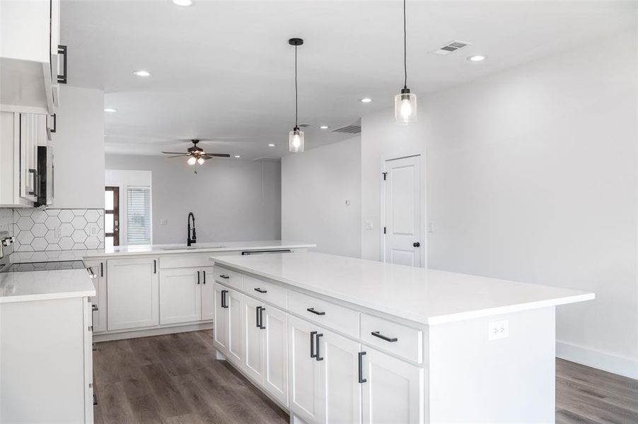 Kitchen featuring ceiling fan, white cabinets, decorative backsplash, sink, and dark wood-type flooring