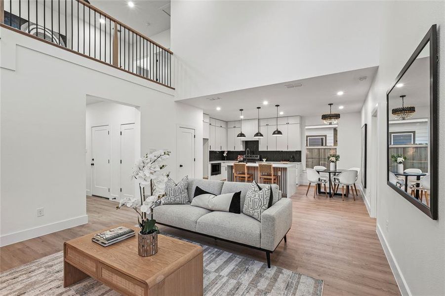 Living room featuring a tiled fireplace, light hardwood / wood-style floors, and a high ceiling