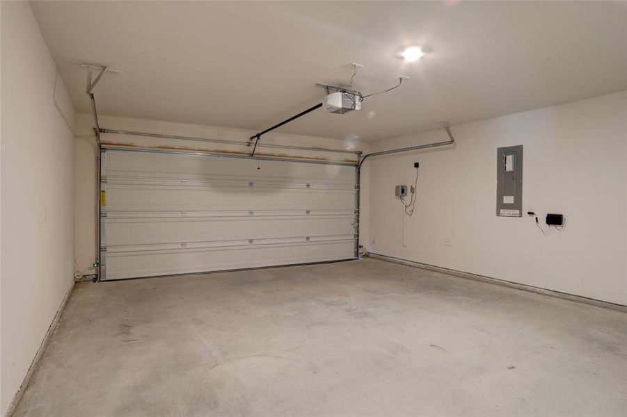 Garage featuring electric panel and a garage door opener