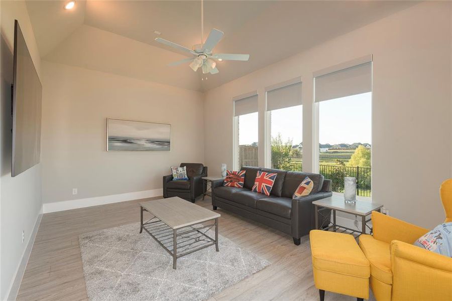 Living room with ceiling fan, vaulted ceiling, and light hardwood / wood-style floors