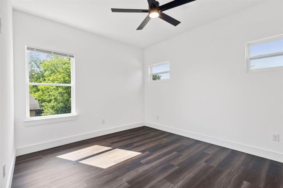 Empty room with ceiling fan and dark wood-type flooring