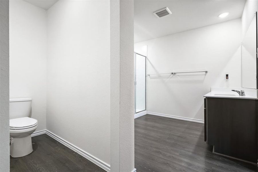 Bathroom featuring vanity, wood-type flooring, a shower with shower door, and toilet