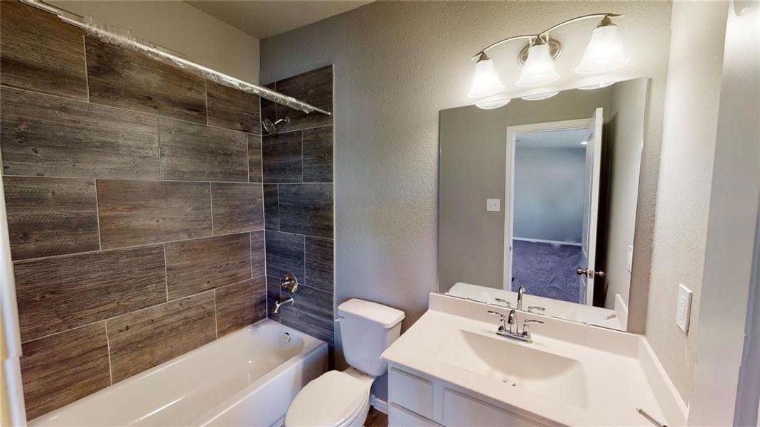 This secondary bathroom features a clean and modern design, complete with a stylish vanity and a combination shower/tub with attractive tile work. It serves as a convenient and comfortable space for family or guests. This is a picture of an Elise Floor Plan with another Saratoga Homes.