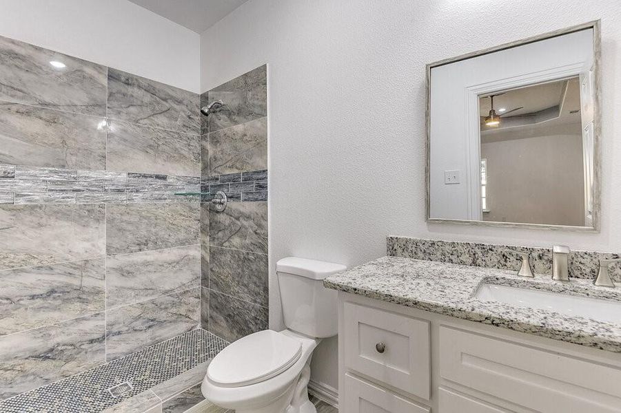 Bathroom with vanity, toilet, and tiled shower