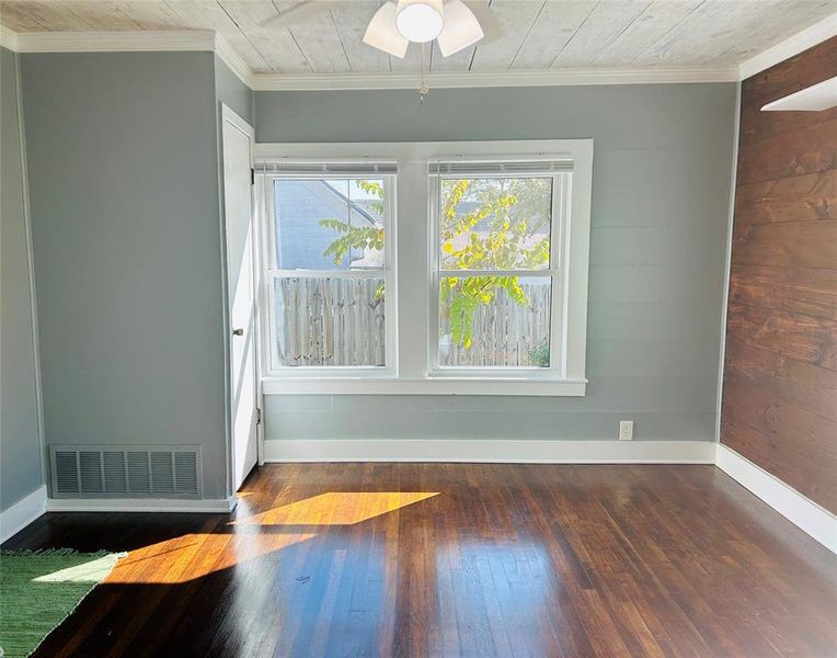 Bedroom, featuring crown molding, dark hardwood / wood-style floors, wooden walls, and ceiling fan