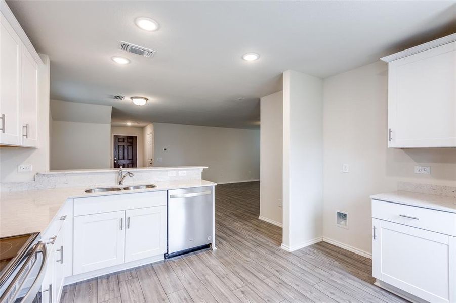 Kitchen with range, white cabinets, sink, dishwasher, and kitchen peninsula