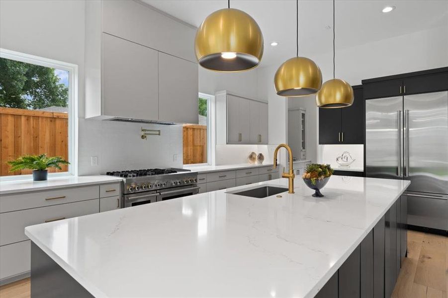 Kitchen featuring light stone counters, pendant lighting, a large island, and high end appliances