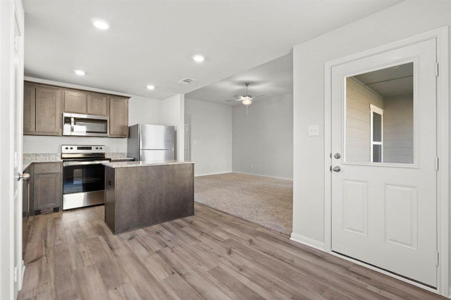 Kitchen featuring a center island, ceiling fan, light hardwood / wood-style flooring, and appliances with stainless steel finishes