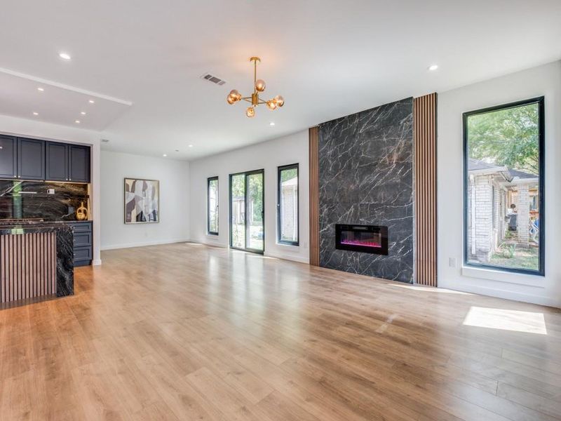 Living room featuring an inviting chandelier, light wood-type flooring, and a premium fireplace