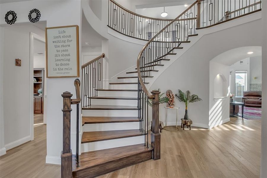 Staircase with a high ceiling and light hardwood / wood-style flooring