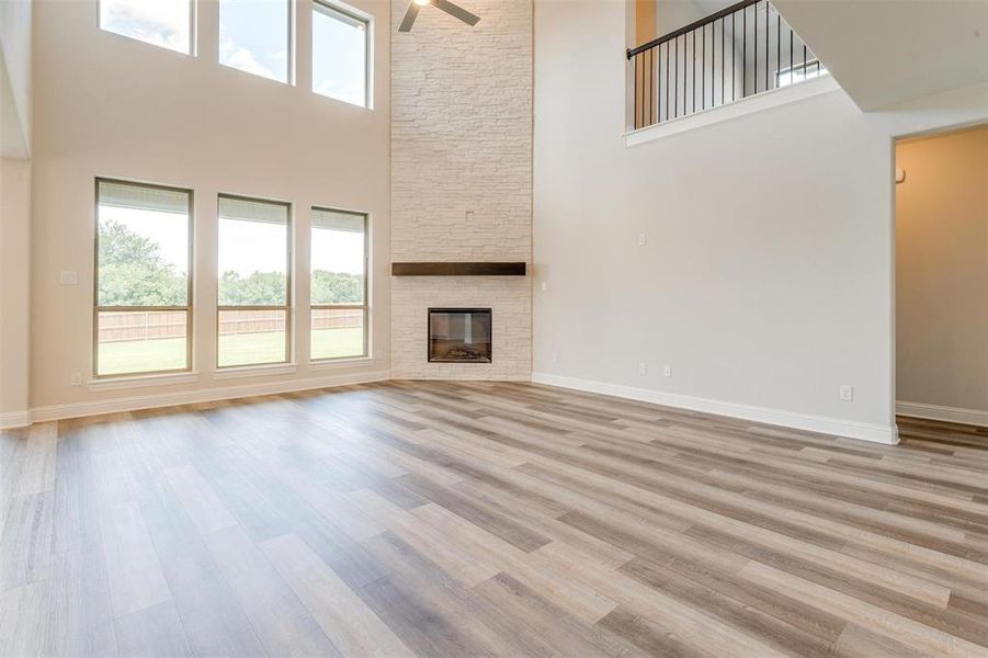 Unfurnished living room with a high ceiling, a fireplace, and light hardwood / wood-style flooring