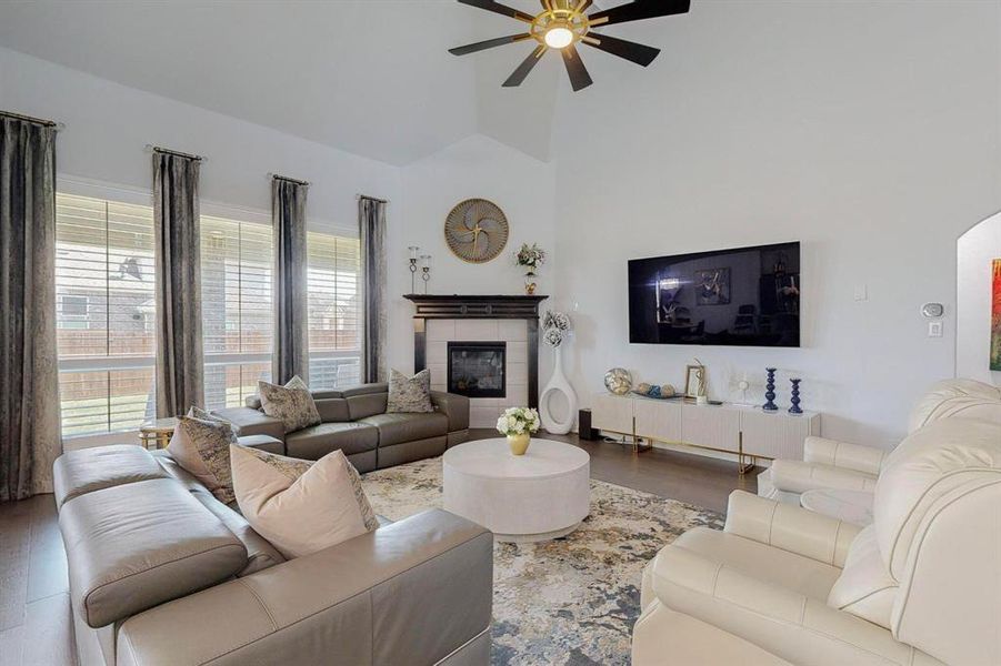 Living room with a fireplace, hardwood / wood-style flooring, high vaulted ceiling, and ceiling fan