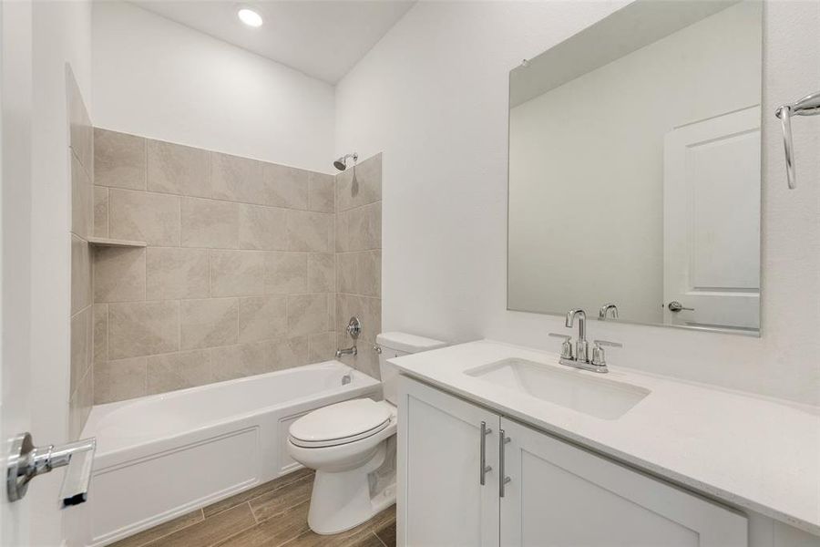 Full bathroom featuring tiled shower / bath combo, vanity, toilet, and wood-type flooring