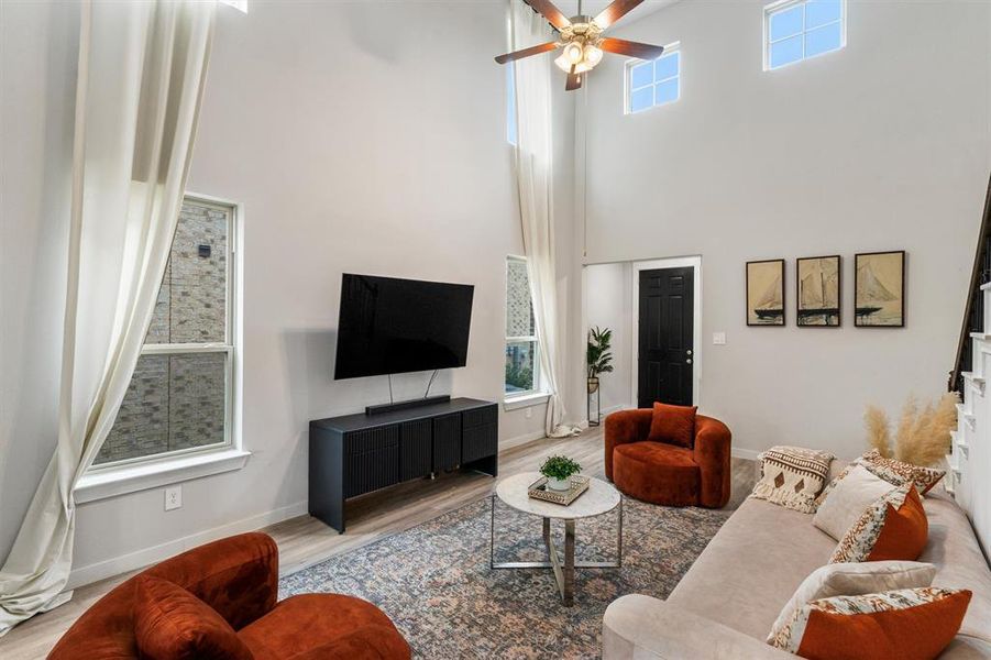 Living room featuring a high ceiling, light hardwood / wood-style floors, and ceiling fan