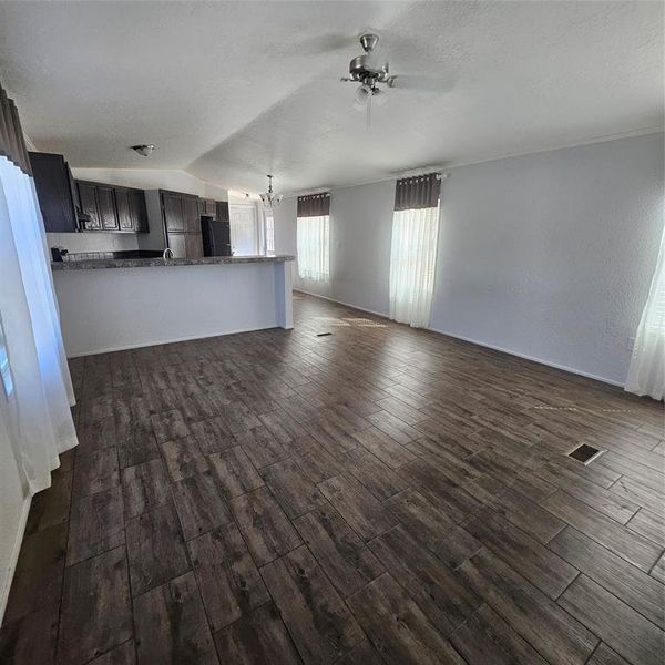 Unfurnished living room with vaulted ceiling, dark hardwood / wood-style floors, sink, and ceiling fan